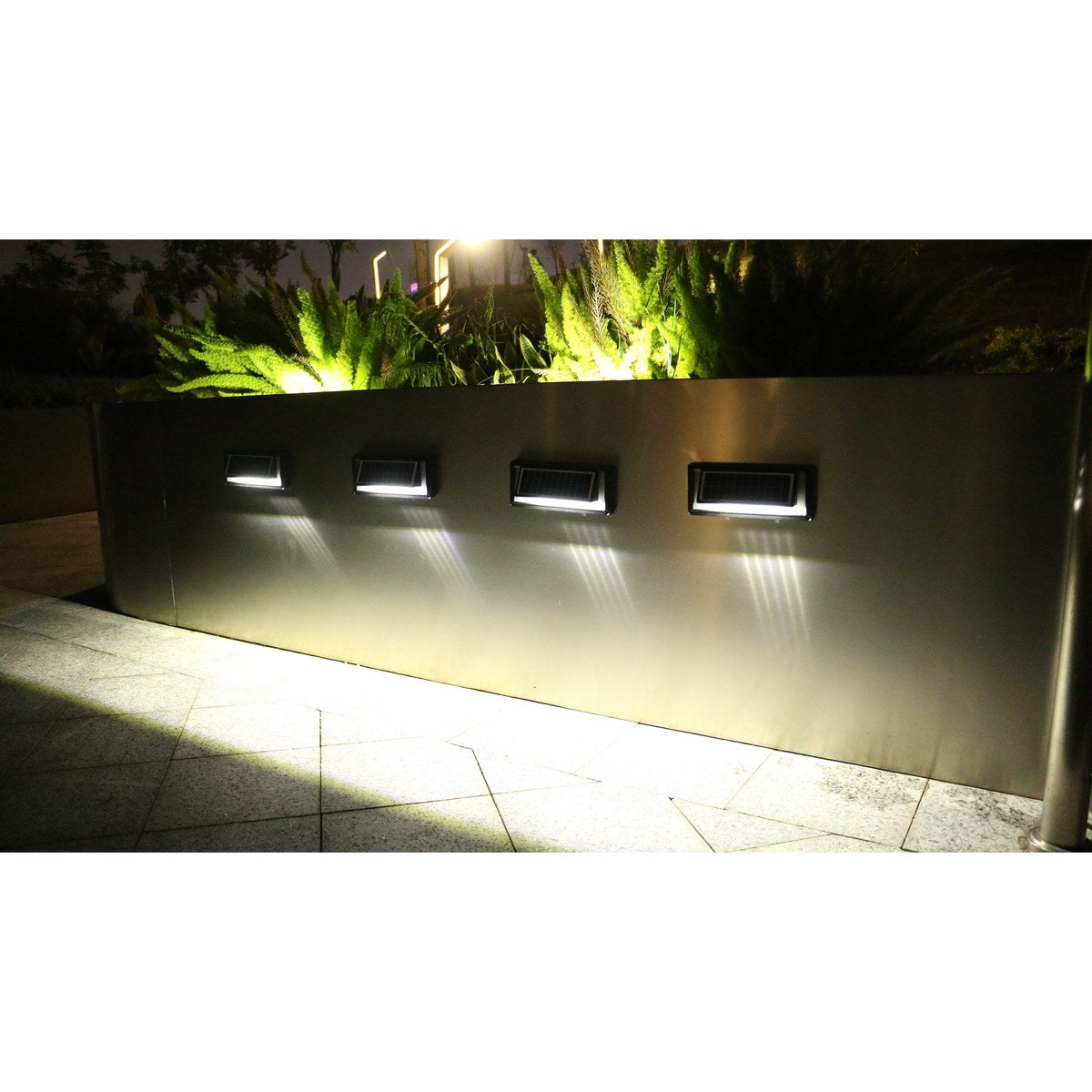 Aluminium solar wall light casting steady white light on an exterior wall