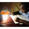 Small portable solar lantern glowing warm white on a camp table