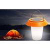 Small portable solar lantern glowing warm white on a camp table