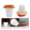 Small portable solar lantern glowing warm white on a camp table
