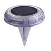 Round solar deck light glowing warm white on timber decking