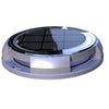 Round solar deck light glowing warm white on timber decking