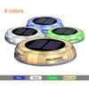 Round solar deck light glowing warm white on timber decking