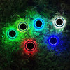 Colour-changing solar lawn light glowing blue in a garden bed