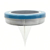 Colour-changing solar lawn light glowing blue in a garden bed